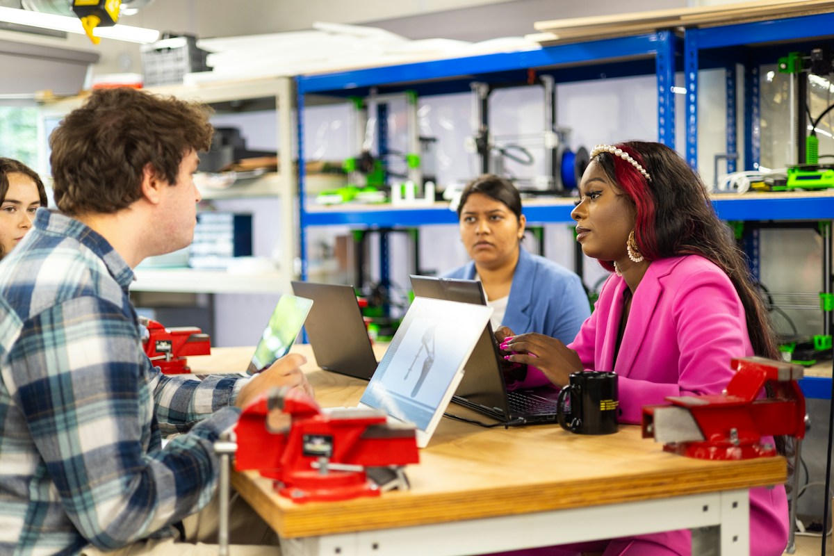 Vier Studierende arbeiten mit Laptops an einem Labortisch
